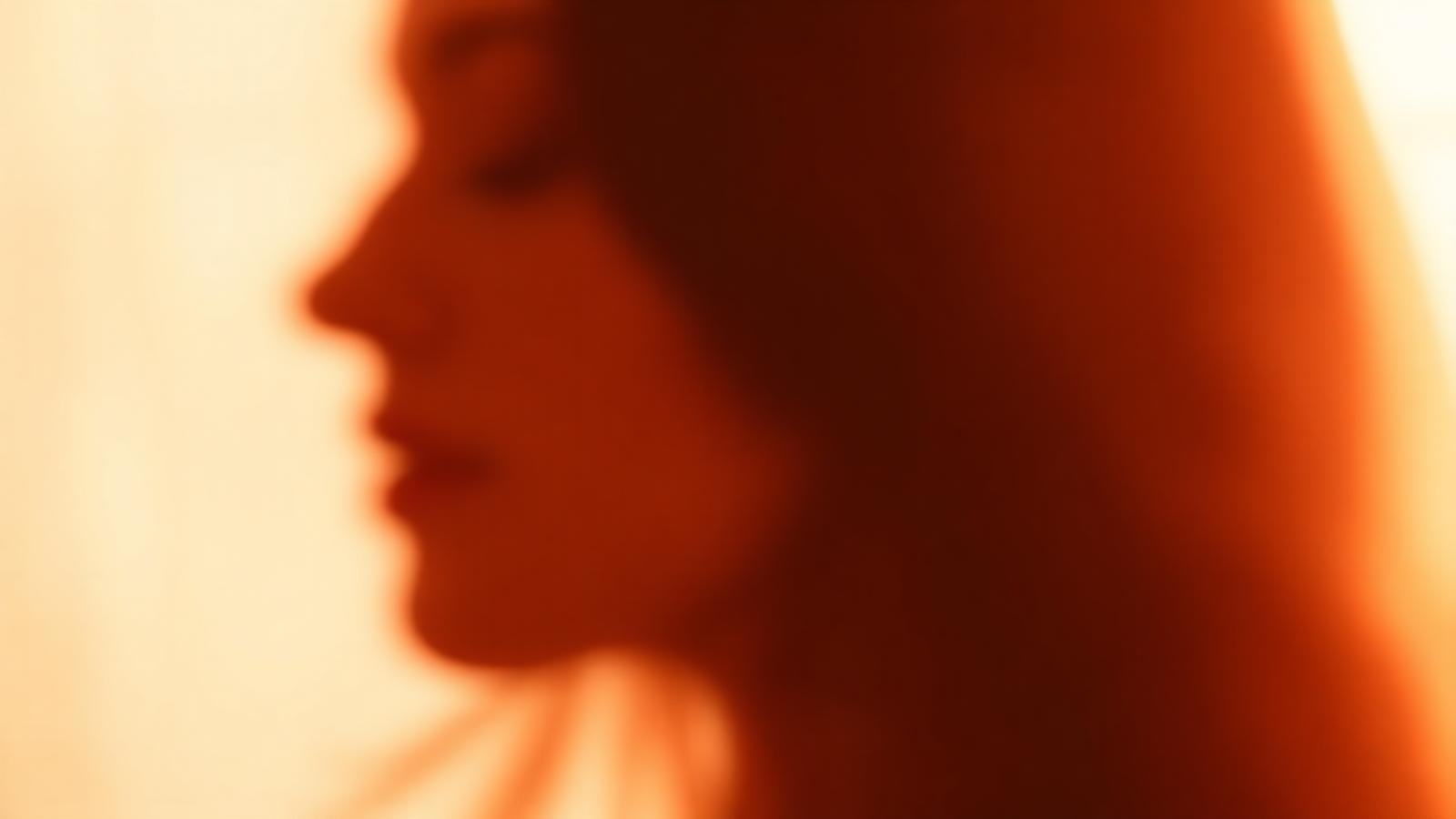 A softly blurred, warmly lit portrait — identity hidden